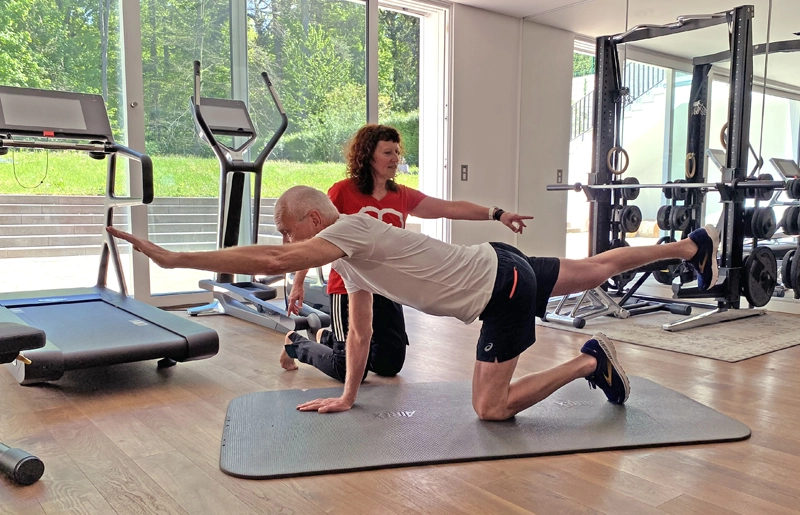 Training bei orthopädischen Beschwerden: Vierfüßlerübung mit gegengleichem Arm- und Beinheben, angeleitet durch die Trainerin.