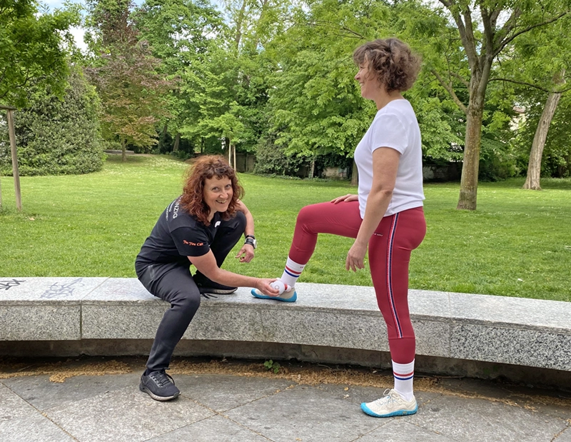 Neuronales Training: Trainerin aktiviert die Rezeptoren am Fußgelenk der Kundin mit Massage-Tool