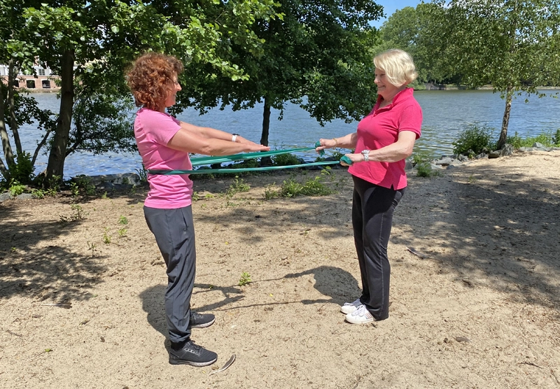 Personal Trainerin in Frankfurt führt mit Seniorin Partner-Übung mit Theraband durch zur Kraftentwicklung im Alter