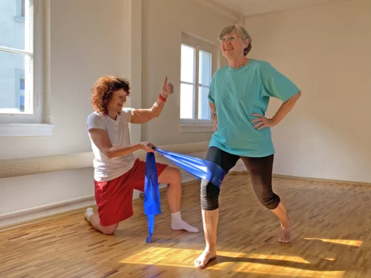 Personal Trainerin in Frankfurt korrigiert Kniestellung mit Theraband beim funktionellen Beinachsentraining zur Prävention von Knieproblemen