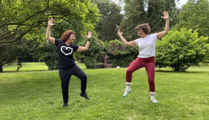 Trainerin in Frankfurt trainiert mit Kundin eine Bauchübung im Park: Gesundheitstraining mit Freude