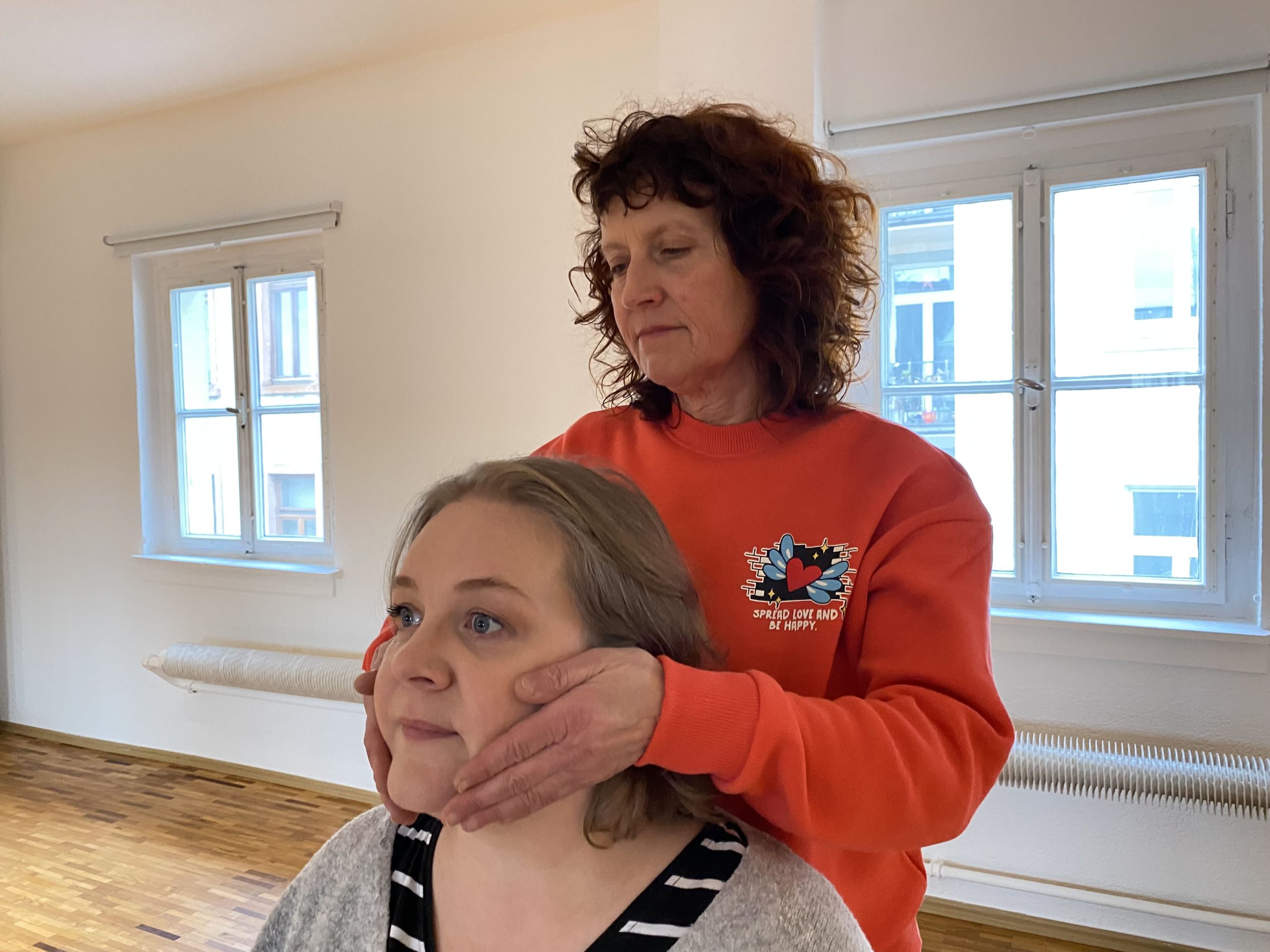 R.E.S.E.T. Kieferbalance: Eine Person sitzt, während ich hinter ihr stehe und sanft meine Hände an ihrem Kiefer und Nacken positioniere.
